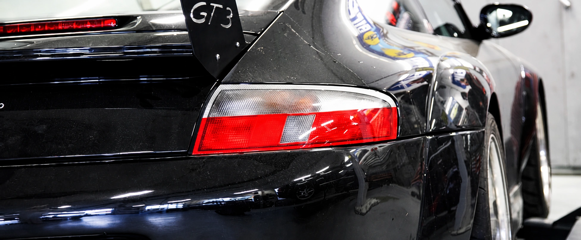 Detail von Heck und Rückleuchte eines schwarzen Porsche in der Werkstatt